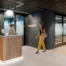 Reception area at an Arcadis office, with a staff member behind a timber-fronted desk and another person walking past the company logo and glass meeting rooms.