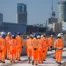 Group of HS2 construction workers in orange PPE walking across a construction site with Birmingham city centre skyline in the background.