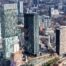 Aerial view of Manchester city centre, showing high-rise commercial buildings, construction developments and railway infrastructure around Manchester Piccadilly station.