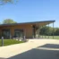 Exterior view of Modulek’s modular sports pavilion at Mindenhurst, showing the wood-effect cladding, cantilevered roof and covered walkway beside the sports pitches.